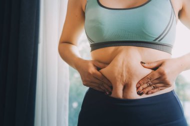 Şişman kadın, şişko, obez kadın el ele tutuşan ölçü bandıyla göbek yağı, kadın diyeti yaşam tarzı konsepti