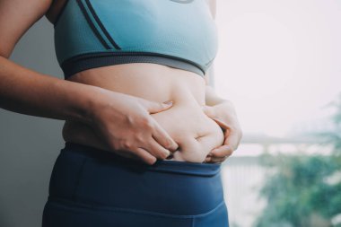 Şişman kadın, şişko, obez kadın el ele tutuşan ölçü bandıyla göbek yağı, kadın diyeti yaşam tarzı konsepti