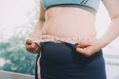 Şişman kadın, şişko, obez kadın el ele tutuşan ölçü bandıyla göbek yağı, kadın diyeti yaşam tarzı konsepti
