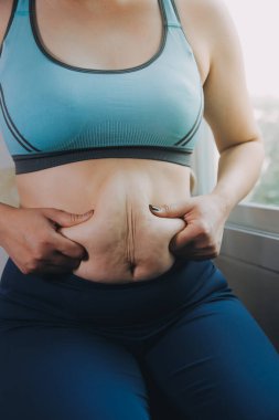 Şişman kadın, şişko, obez kadın el ele tutuşan ölçü bandıyla göbek yağı, kadın diyeti yaşam tarzı konsepti