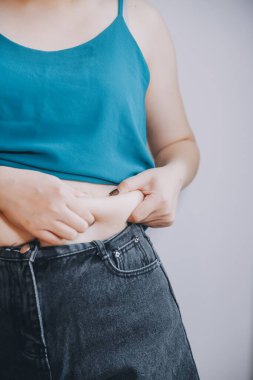 Şişman kadın, şişko, obez kadın el ele tutuşan ölçü bandıyla göbek yağı, kadın diyeti yaşam tarzı konsepti