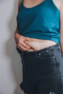 Şişman kadın, şişko, obez kadın el ele tutuşan ölçü bandıyla göbek yağı, kadın diyeti yaşam tarzı konsepti