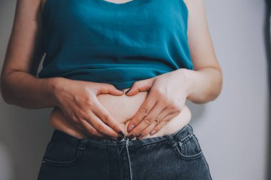 Şişman kadın, şişko, obez kadın el ele tutuşan ölçü bandıyla göbek yağı, kadın diyeti yaşam tarzı konsepti