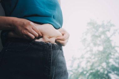 Şişman kadın, şişko, obez kadın el ele tutuşan ölçü bandıyla göbek yağı, kadın diyeti yaşam tarzı konsepti