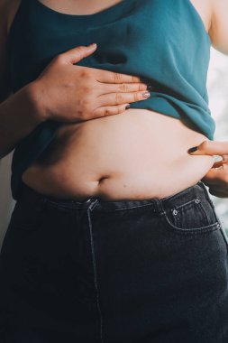 Şişman kadın, şişko, obez kadın el ele tutuşan ölçü bandıyla göbek yağı, kadın diyeti yaşam tarzı konsepti