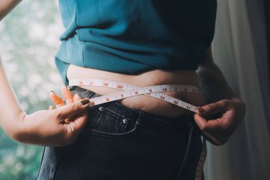 Şişman kadın, şişko, obez kadın el ele tutuşan ölçü bandıyla göbek yağı, kadın diyeti yaşam tarzı konsepti