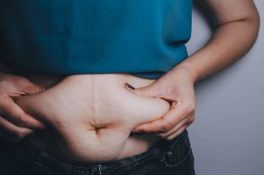 Şişman kadın, şişko, obez kadın el ele tutuşan ölçü bandıyla göbek yağı, kadın diyeti yaşam tarzı konsepti