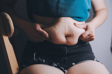 Şişman kadın, şişko, obez kadın el ele tutuşan ölçü bandıyla göbek yağı, kadın diyeti yaşam tarzı konsepti