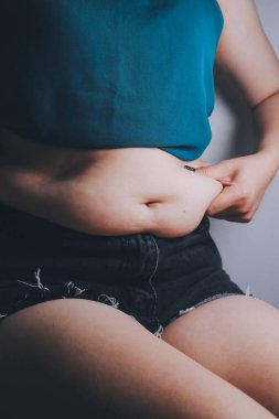 Şişman kadın, şişko, obez kadın el ele tutuşan ölçü bandıyla göbek yağı, kadın diyeti yaşam tarzı konsepti