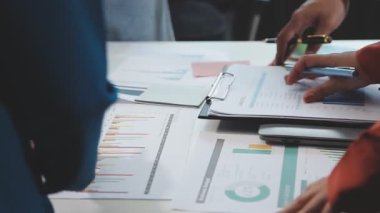 bir grup iş adamı modern ofiste belgeleri tartışıyor.