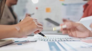 Genç iş adamları birlikte çalışıyor ve modern ofis odasında mali raporları tartışıyorlar.