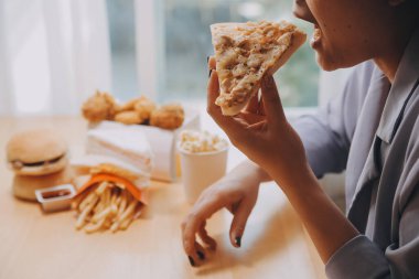 Restoranda pizza dilimi tutan bir kadın resmi.