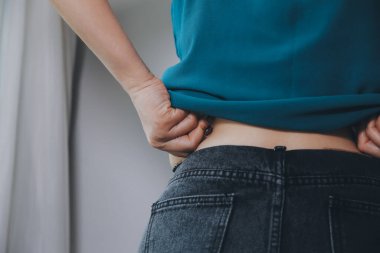 Şişman kadın, şişko, obez kadın el ele tutuşan ölçü bandıyla göbek yağı, kadın diyeti yaşam tarzı konsepti