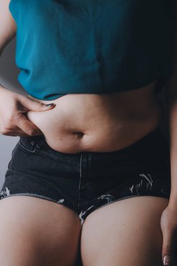 Şişman kadın, şişko, obez kadın el ele tutuşan ölçü bandıyla göbek yağı, kadın diyeti yaşam tarzı konsepti