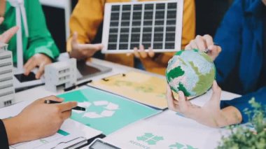 Genç Asyalı iş adamları yeşil bir ortamda tablet ve küre kullanarak birlikte çalışıyorlar..