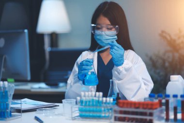 Kendini adamış bir grup bilim adamı tıbbi laboratuvarda kimyasal deney yapıyor. Aşı ilacı veya antibiyotik geliştirmek için pipetten deney tüpüne kesin miktarda sıvı döküyorlar. Neoterik