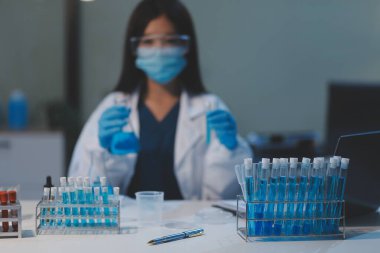 Kendini adamış bir grup bilim adamı tıbbi laboratuvarda kimyasal deney yapıyor. Aşı ilacı veya antibiyotik geliştirmek için pipetten deney tüpüne kesin miktarda sıvı döküyorlar. Neoterik