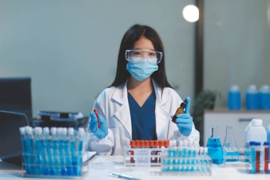 Kendini adamış bir grup bilim adamı tıbbi laboratuvarda kimyasal deney yapıyor. Aşı ilacı veya antibiyotik geliştirmek için pipetten deney tüpüne kesin miktarda sıvı döküyorlar. Neoterik