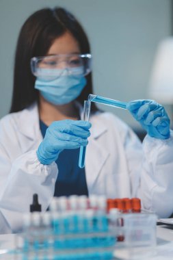 Kendini adamış bir grup bilim adamı tıbbi laboratuvarda kimyasal deney yapıyor. Aşı ilacı veya antibiyotik geliştirmek için pipetten deney tüpüne kesin miktarda sıvı döküyorlar. Neoterik