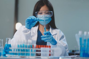 Kendini adamış bir grup bilim adamı tıbbi laboratuvarda kimyasal deney yapıyor. Aşı ilacı veya antibiyotik geliştirmek için pipetten deney tüpüne kesin miktarda sıvı döküyorlar. Neoterik