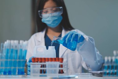 Kendini adamış bir grup bilim adamı tıbbi laboratuvarda kimyasal deney yapıyor. Aşı ilacı veya antibiyotik geliştirmek için pipetten deney tüpüne kesin miktarda sıvı döküyorlar. Neoterik