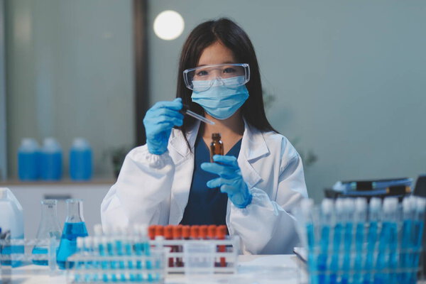 Group of dedicated scientist conduct chemical experiment in medical laboratory, carefully drop precise amount of liquid from pipette into test tube for vaccine drug or antibiotic development. Neoteric