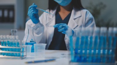 Kendini adamış bir grup bilim adamı tıbbi laboratuvarda kimyasal deney yapıyor. Aşı ilacı veya antibiyotik geliştirmek için pipetten deney tüpüne kesin miktarda sıvı döküyorlar. Neoterik