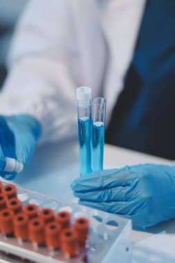Kendini adamış bir grup bilim adamı tıbbi laboratuvarda kimyasal deney yapıyor. Aşı ilacı veya antibiyotik geliştirmek için pipetten deney tüpüne kesin miktarda sıvı döküyorlar. Neoterik