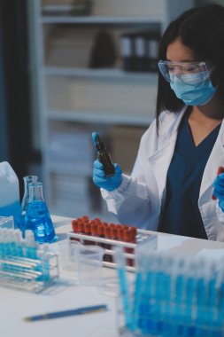 Kendini adamış bir grup bilim adamı tıbbi laboratuvarda kimyasal deney yapıyor. Aşı ilacı veya antibiyotik geliştirmek için pipetten deney tüpüne kesin miktarda sıvı döküyorlar. Neoterik