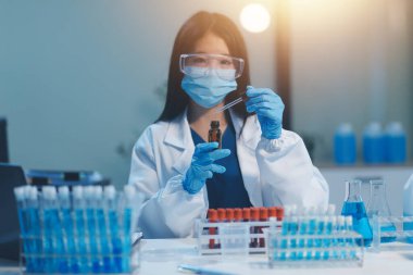 Kendini adamış bir grup bilim adamı tıbbi laboratuvarda kimyasal deney yapıyor. Aşı ilacı veya antibiyotik geliştirmek için pipetten deney tüpüne kesin miktarda sıvı döküyorlar. Neoterik