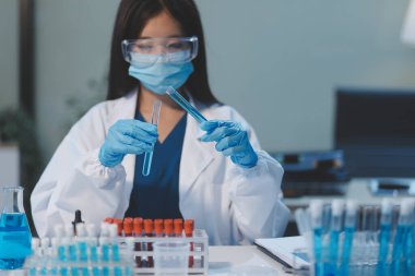 Kendini adamış bir grup bilim adamı tıbbi laboratuvarda kimyasal deney yapıyor. Aşı ilacı veya antibiyotik geliştirmek için pipetten deney tüpüne kesin miktarda sıvı döküyorlar. Neoterik