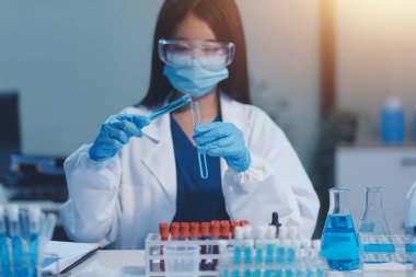 Kendini adamış bir grup bilim adamı tıbbi laboratuvarda kimyasal deney yapıyor. Aşı ilacı veya antibiyotik geliştirmek için pipetten deney tüpüne kesin miktarda sıvı döküyorlar. Neoterik