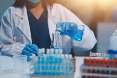 Kendini adamış bir grup bilim adamı tıbbi laboratuvarda kimyasal deney yapıyor. Aşı ilacı veya antibiyotik geliştirmek için pipetten deney tüpüne kesin miktarda sıvı döküyorlar. Neoterik