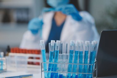 Kendini adamış bir grup bilim adamı tıbbi laboratuvarda kimyasal deney yapıyor. Aşı ilacı veya antibiyotik geliştirmek için pipetten deney tüpüne kesin miktarda sıvı döküyorlar. Neoterik