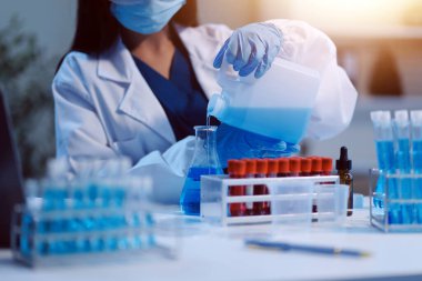 Kendini adamış bir grup bilim adamı tıbbi laboratuvarda kimyasal deney yapıyor. Aşı ilacı veya antibiyotik geliştirmek için pipetten deney tüpüne kesin miktarda sıvı döküyorlar. Neoterik