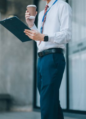 Mutlu iş adamı kahve içiyor ve ofisinin önünde cep telefonu kullanıyor..