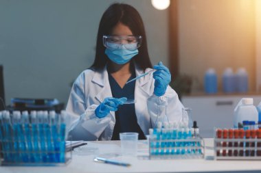 Kendini adamış bir grup bilim adamı tıbbi laboratuvarda kimyasal deney yapıyor. Aşı ilacı veya antibiyotik geliştirmek için pipetten deney tüpüne kesin miktarda sıvı döküyorlar. Neoterik