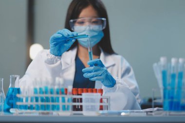 Kendini adamış bir grup bilim adamı tıbbi laboratuvarda kimyasal deney yapıyor. Aşı ilacı veya antibiyotik geliştirmek için pipetten deney tüpüne kesin miktarda sıvı döküyorlar. Neoterik