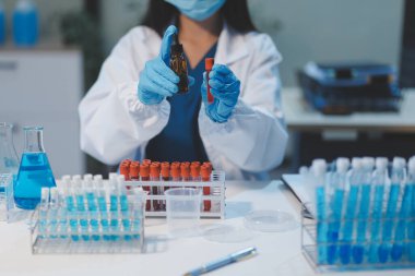 Kendini adamış bir grup bilim adamı tıbbi laboratuvarda kimyasal deney yapıyor. Aşı ilacı veya antibiyotik geliştirmek için pipetten deney tüpüne kesin miktarda sıvı döküyorlar. Neoterik