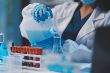 Kendini adamış bir grup bilim adamı tıbbi laboratuvarda kimyasal deney yapıyor. Aşı ilacı veya antibiyotik geliştirmek için pipetten deney tüpüne kesin miktarda sıvı döküyorlar. Neoterik
