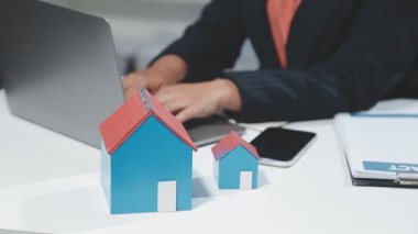 Ofiste dizüstü bilgisayarı ve ev modelini kullanan işadamı eli, emlak ve emlak kavramı, emlak işi