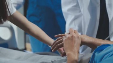 Hastanedeki doktor el ele tutuşup hastaların ellerini kontrol ediyor..