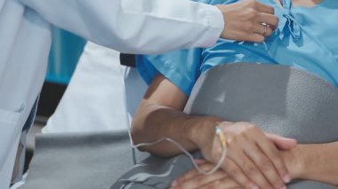 Üniformalı doktor ve eldivenler hastane koğuşunda nabzı kontrol ediyor.