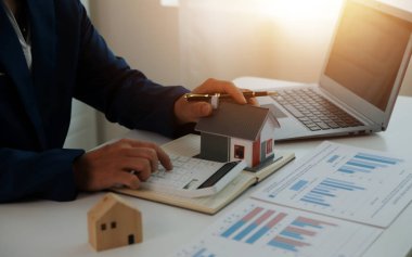 Businessmen holding pens, signing home titles with insurance, care about real estate services and the idea of real estate agents offering interest in installments to their customers.