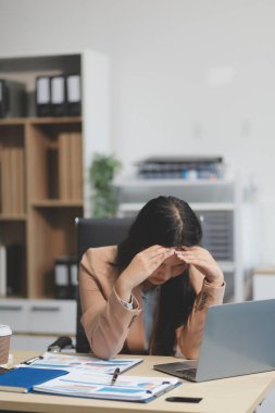 Yorgun ve Asyalı bir kadının portresi ofiste vergi bilgisayarıyla çalışıyor. Üzgün, mutsuz, endişeli, depresyon ya da çalışan hayatı stres konsepti