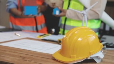 Bir iş yerinde bir plan ve tabletle çalışan mimar