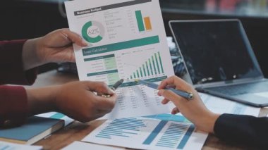 İş adamları dizüstü bilgisayarda çalışıyor ve masadaki grafikleri analiz ediyor