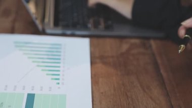 İşadamı ofis masasında dizüstü bilgisayarla ve belgelerle çalışıyor.