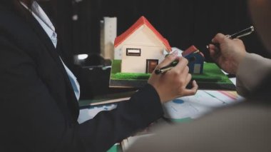 Masasında ev modeli olan bir iş kadınının elini kapat..