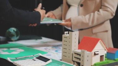 Emlakçı ev modelini tutuyor, model ev modelini gösteriyor, yeni bir ev alıyor, emlak sigortası yaptırıyor, ev alıyor, emlak sigortası yaptırıyor.